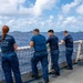 U.S. Coast Guardsmen observe multinational ships sail in formation during RIMPAC 2026
