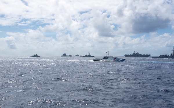 U.S. Coast Guardsmen observe multinational ships sail in formation during RIMPAC 2026