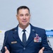 A U.S. Air Force senior non-commissioned officer named Ehlert is speaking at a podium bearing the insignia of the 162nd Wing. He is wearing the Air Force Service Dress uniform with numerous service ribbons, a Senior Master Sergeant or Chief Master Sergeant rank insignia on his sleeve, and a name tag reading 'EHLERT'. The setting appears to be an official military ceremony or briefing.