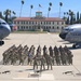 A formal military unit photograph taken on the flight line at March Field Air Reserve Base in California. A large formation of U.S. Air Force personnel in camouflage uniforms are posed between two aircraft — a C-17 Globemaster III (tail number 5144, 452nd AMW) on the left and a KC-135 Stratotanker on the right. The historic March Field building with its red-tile roof and American flag is visible in the background.