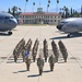 A formal military formation photograph taken on the flight line at March Field, showing U.S. Air Force personnel arranged in a V-shaped formation on the tarmac. Two U.S. Air Force aircraft flank the formation — a C-17 Globemaster III on the left (tail number 5144, 452nd AMW) and a KC-135 Stratotanker on the right. The historic March Field administration building is visible in the background, surrounded by palm trees.
