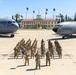 A large group of U.S. Air Force personnel in OCP (Operational Camouflage Pattern) uniforms are posed in formation on a flight line at March Field (March Air Reserve Base), California. Two U.S. Air Force aircraft flank the formation, with the historic March Field building visible in the background. A guidon bearer is visible in the front of the formation, suggesting this is an official unit photograph.
