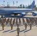 A formal military group photograph taken on the flight line at March Field Air Reserve Base, featuring a large formation of U.S. Air Force personnel in OCP (Operational Camouflage Pattern) uniforms. A KC-135 Stratotanker aircraft bearing the markings '452 AMW' (Air Mobility Wing) and unit insignia is prominently displayed behind the formation. The building in the background is labeled 'MARCH FIELD,' identifying this as March Air Reserve Base in Riverside, California.