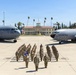 A formal military unit formation photograph taken on the flight line at March Field Air Reserve Base, with personnel in OCP (Operational Camouflage Pattern) uniforms arranged in a V-shaped formation. Two U.S. Air Force aircraft flank the formation — a C-17 Globemaster III (tail number 5144, 452nd AMW) on the left and what appears to be a KC-135 Stratotanker on the right. The historic March Field headquarters building is visible in the background with an American flag flying above it.