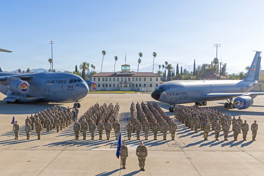 A large U.S. Air Force unit formation photograph taken on a flight line at March Field (March Air Reserve Base), California. Military personnel in camouflage uniforms are arranged in formal parade formation between two U.S. Air Force aircraft. The scene includes a C-17 Globemaster III on the left and a KC-135 Stratotanker on the right, with the historic March Field building visible in the background.