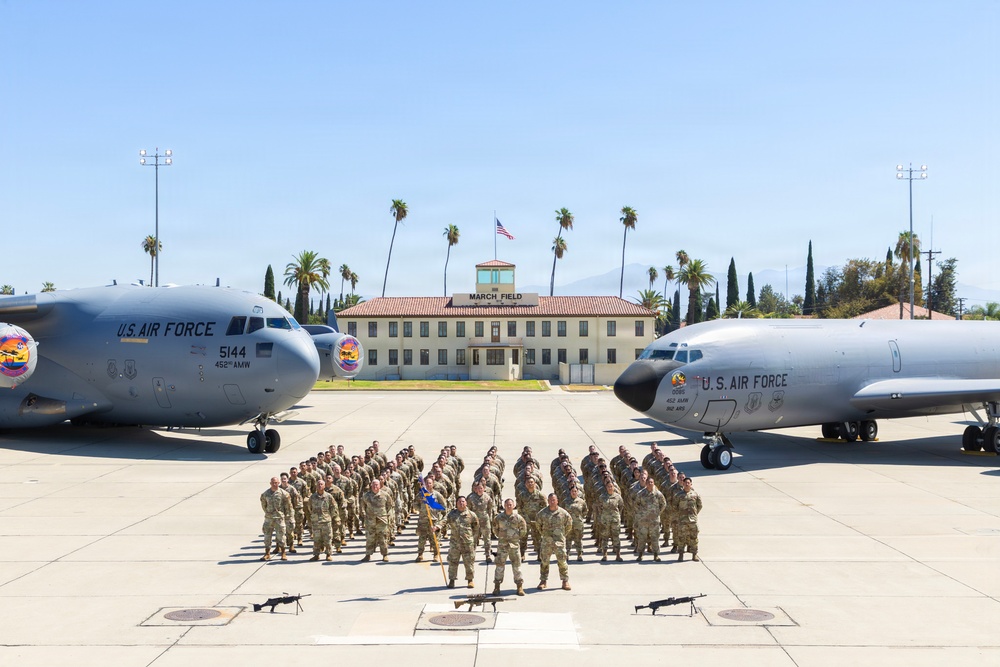 A formal group photograph of U.S. Air Force personnel assembled on the flight line at March Field (March Air Reserve Base), California. Two military aircraft flank the formation — a C-17 Globemaster III (tail number 5144, 452nd AMW) on the left and a KC-135 Stratotanker on the right. The historic March Field headquarters building is visible in the background with an American flag flying above it.