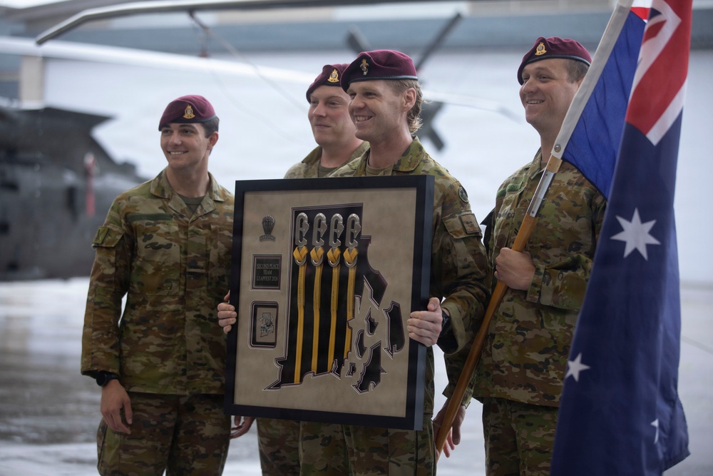 Four military personnel wearing Australian Army camouflage uniforms and maroon berets are posing together during what appears to be an awards ceremony. One soldier is holding a framed plaque that reads 'Second Place Team' with parachute-related insignia and yellow lanyards. Another soldier on the right is carrying the Australian national flag.