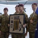Four military personnel wearing Australian Army camouflage uniforms and maroon berets are posing together during what appears to be an awards ceremony. One soldier is holding a framed plaque that reads 'Second Place Team' with parachute-related insignia and yellow lanyards. Another soldier on the right is carrying the Australian national flag.