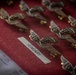 The image shows a collection of military aviation wing badges arranged on a red velvet surface. A label reading 'HUNGARY' is visible, suggesting these badges are organized by country, likely for a multinational military ceremony or award event. A partially visible document with fields for signatures is also present in the lower left corner.