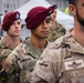 A group of military personnel in formation, wearing maroon berets indicating airborne/paratrooper units. At least two different national uniforms are visible, suggesting a multinational military exercise or ceremony. The soldiers appear to be at attention or standing in a formal assembly.
