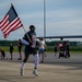 Staff Sgt. Kibingira Carries U.S. Flag Across Runway 5K Finish Line
