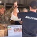 A U.S. Air Force service member in camouflage uniform is receiving a food bag at RAAF Base Tindal's 'Harry's Hut' food service station. Another individual wearing an 'AIR FORCE' t-shirt is handing over the bag across a counter. The scene depicts a military dining or food distribution operation at an Australian Royal Air Force base.