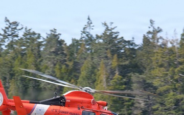 U.S. Coast Guard MH-65 Dolphin Helicopter 6603 in Flight Near Forested Coastline