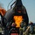Gulfport CRTC Live Fire Training Exercise A group of firefighters in full protective gear and SCBA (Self-Contained Breathing Apparatus) units are conducting a live fire training exercise at what appears to be an aircraft rescue and firefighting (ARFF) training facility. The trainees are approaching a large metal aircraft fuselage simulator engulfed in active flames. One trainee is visibly wearing a jacket marked 'CRTC', indicating an organized training program.