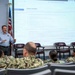 A civilian instructor or counselor is presenting a briefing on 'State Licenses' to a group of U.S. Navy sailors in a classroom or conference room setting. The projected screen displays information about state licensing requirements, referencing Navy COOL (Credentialing Opportunities On-Line) funding assistance. The audience consists of multiple sailors in Navy Working Uniform (NWU) camouflage pattern seated in rows.