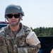 A U.S. Air Force service member named Kern is photographed in an outdoor field environment. He is wearing OCP (Operational Camouflage Pattern) uniform, a tactical helmet, and sunglasses, with his name tape and unit patch clearly visible. The setting appears to be a training or operational exercise near a vehicle.