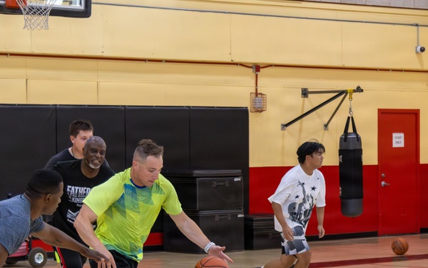 U.S. Marines and local community members participate in a pickup basketball game