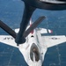 An aerial photograph taken from a tanker aircraft showing a USAF Thunderbirds F-16 Fighting Falcon during an aerial refueling operation. The fighter jet is viewed from directly above and behind, with the tanker's refueling boom extending toward the aircraft's receptacle. The patchwork agricultural landscape below confirms the aircraft are flying at altitude over a rural area.
