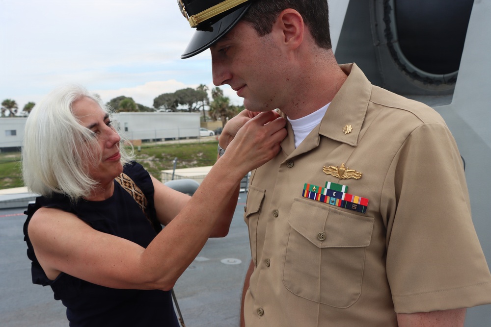 Captain Mary Hays, Commanding Officer, USS Ted Stevens (DDG 128), promotes Weapons Officer, LT Zachary Wasson, to the rank of Lieutenant Commander. He was pinned to his new rank by his mother.