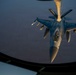 An aerial refueling operation is captured from the boom operator's window of a tanker aircraft, showing an F-16 Fighting Falcon receiving fuel via a refueling boom. The image is taken at dusk or dawn, with warm golden light illuminating the fighter jet against a dark blue sky. The word 'COYOTES' is visible on the refueling boom, suggesting a unit designation.