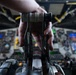 A close-up photograph of a pilot's hand gripping multiple throttle levers in a large aircraft cockpit, with levers numbered 1, 2, and 3 visible. Labels reading 'START' and 'CUT-OFF' are visible on the throttle quadrant. The background shows a complex instrument panel with multiple digital displays and analog gauges, consistent with a large commercial or military transport aircraft.