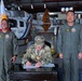A formal military signing ceremony taking place inside an aviation hangar, featuring a U.S. Army officer seated at a desk signing documents, flanked by two Philippine military officers in flight suits. A Philippine Coast Guard helicopter is visible in the background along with Philippine and military unit flags. The setting suggests a bilateral military cooperation or agreement signing event.