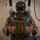 Leapfest 2026 (Pre Jump Training) A military personnel member is suspended in a parachute training harness rig while wearing a virtual reality headset, simulating a parachute jump experience. The individual is dressed in multicam/MTP camouflage uniform and is gripping what appears to be a simulated parachute reserve handle. This appears to be a military parachute training simulator combining VR technology with physical harness equipment.
