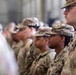 A group of U.S. Army soldiers standing in formation, wearing Operational Camouflage Pattern (OCP) uniforms. The soldiers appear to be at attention during a formal military ceremony or briefing held indoors. Both male and female soldiers of diverse backgrounds are visible in the formation.