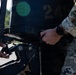 Two military personnel in different camouflage uniforms are working on what appears to be an outboard boat motor marked with the number '24'. One individual is wearing OCP (Operational Camouflage Pattern) uniform while the other appears to be in MARPAT or similar pattern. They are performing maintenance or assembly work on the motor using hand tools.