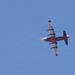 A red and white multi-engine turboprop aircraft is photographed from below against a clear blue sky. The aircraft bears the markings 'COULSON' on the wing and 'FIRE' on the tail, identifying it as a Coulson Aviation firefighting/aerial tanker aircraft. The plane appears to be in level flight, viewed from a ground-level perspective.