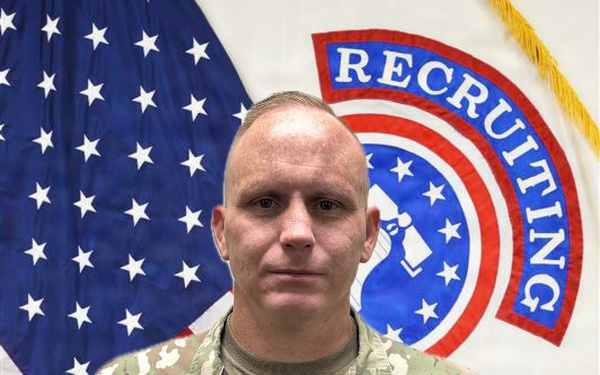 A U.S. Army soldier named Carlson poses for an official portrait in Army Combat Uniform (ACU/OCP pattern). He stands in front of a U.S. flag and a U.S. Army Recruiting Command flag. His rank insignia indicates he holds the grade of Sergeant Major or Command Sergeant Major.
