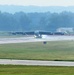 A large multi-engine bomber aircraft, consistent with a B-52 Stratofortress, is taxiing or rolling on a wet runway at a military airfield. The runway surface appears wet, likely from recent rain, with visible spray or mist around the landing gear. Distance markers numbered 2, 3, and 4 are visible along the runway edge.