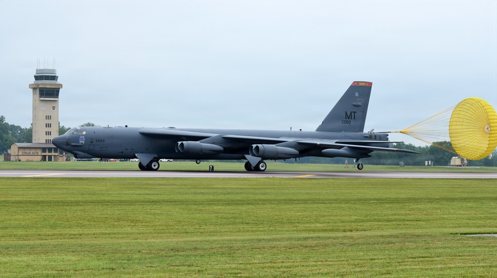 A U.S. Air Force B-52 Stratofortress strategic bomber is landing on a runway with its yellow drag parachute deployed for deceleration. The aircraft bears the tail code 'MT' and serial number '0060', indicating it belongs to the Montana-based 5th Bomb Wing at Minot Air Force Base. A control tower with 'Offutt AFB' signage is visible in the background, suggesting this was taken at Offutt Air Force Base, Nebraska.