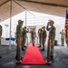 A formal U.S. Navy military ceremony is taking place aboard the USS Kansas City (LCS-22), a Littoral Combat Ship. Personnel in Navy Working Uniform (NWU) camouflage are rendering salutes along a red carpet under a large tent on the ship's deck. A podium bearing the ship's name plate 'USS KANSAS CITY LCS-22' is visible on the right, alongside American and POW/MIA flags.