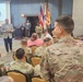 A formal listening session Q&amp;A is taking place at Fort Buchanan, Puerto Rico, with a civilian speaker addressing an audience of military personnel in OCP (Operational Camouflage Pattern) uniforms and some civilians. A podium bearing the 'Fort Buchanan Puerto Rico' insignia is visible at the front, with a projection screen displaying 'LISTENING SESSION Q&amp;As' and a Q&amp;A graphic. Several flags, including the U.S. flag and what appears to be military branch flags, are displayed in the background.