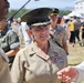 A female U.S. Marine Corps officer wearing a service uniform with two-star rank insignia (Major General) and multiple service ribbons is engaged in conversation at what appears to be an outdoor military event or air show. She is wearing the distinctive Marine Corps service cover with gold oak leaf embroidery indicating senior officer rank. The setting appears to be in an East Asian country, likely South Korea or Japan, based on the crowd and surrounding personnel.