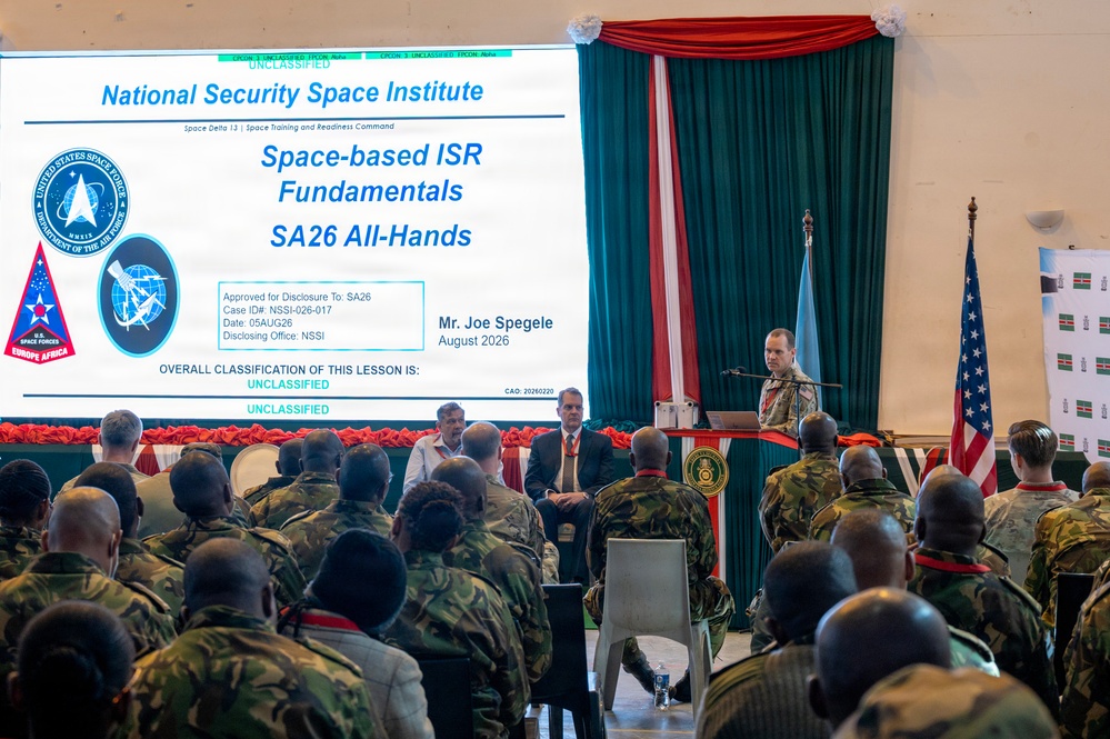 A military briefing is being conducted by Mr. Joe Spegele from the National Security Space Institute on 'Space-based ISR Fundamentals' for an SA26 All-Hands audience in August 2026. The presentation slide is marked UNCLASSIFIED and is affiliated with Space Delta 13 and Space Training and Readiness Command under U.S. Space Forces Europe Africa. An audience of military personnel in camouflage uniforms is seated facing the presenter at a podium.