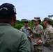 The image shows a group of U.S. Army Military Police (MP) soldiers engaged in a discussion with what appear to be Panamanian security forces personnel, likely during a joint training or liaison event. Two U.S. Army soldiers wearing MultiCam uniforms with 'MP' patches and Africa Command shoulder sleeve insignia are speaking with personnel in olive-green uniforms. One individual in the foreground wears a cap reading 'Dios y Patria' (God and Homeland), a Panamanian national motto, suggesting a bilateral military cooperation context.