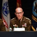 Three military officers are seated at a panel table during what appears to be a formal military conference or symposium. The central figure, identified by a nameplate as LTG Rick Zellmann, is speaking at a microphone while wearing a U.S. Army dress uniform with three-star rank insignia. Military flags including a U.S. Navy flag are visible in the background.