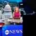 A female news anchor is seated at a broadcast desk delivering a report on the ABC News network. The studio features a large backdrop displaying the United States Capitol building in Washington D.C. A professional broadcast camera is visible in the foreground, partially silhouetted.
