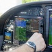The image shows the cockpit interior of a small aircraft with tail number N1017H, featuring Advanced Cock 8800 avionics displays. A pilot's hand wearing a watch is interacting with the central EFIS/MFD screen, which is displaying a TAXI checklist on page 4 of 16. The cockpit is equipped with modern glass panel avionics including navigation displays, autopilot controls, and a moving map.