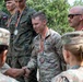 A military awards ceremony featuring soldiers from multiple nations, including US Army personnel and Polish military members, receiving medals with red, yellow, and blue ribbons. The central figure, identified by name tape as 'WALP' from the US Army, is wearing a bronze (3rd place) medal and shaking hands with another soldier. The setting appears to be an outdoor multinational military competition or exercise.