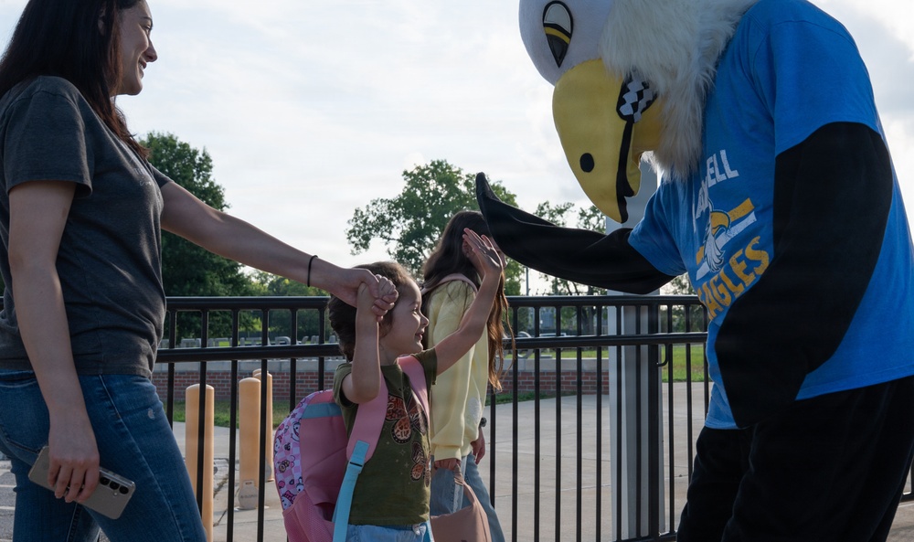Airmen and civilians cheer students on their first day of school