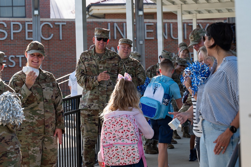 Airmen and civilians cheer students on their first day of school