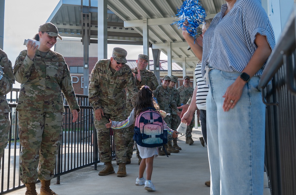 Airmen and civilians cheer students on their first day of school