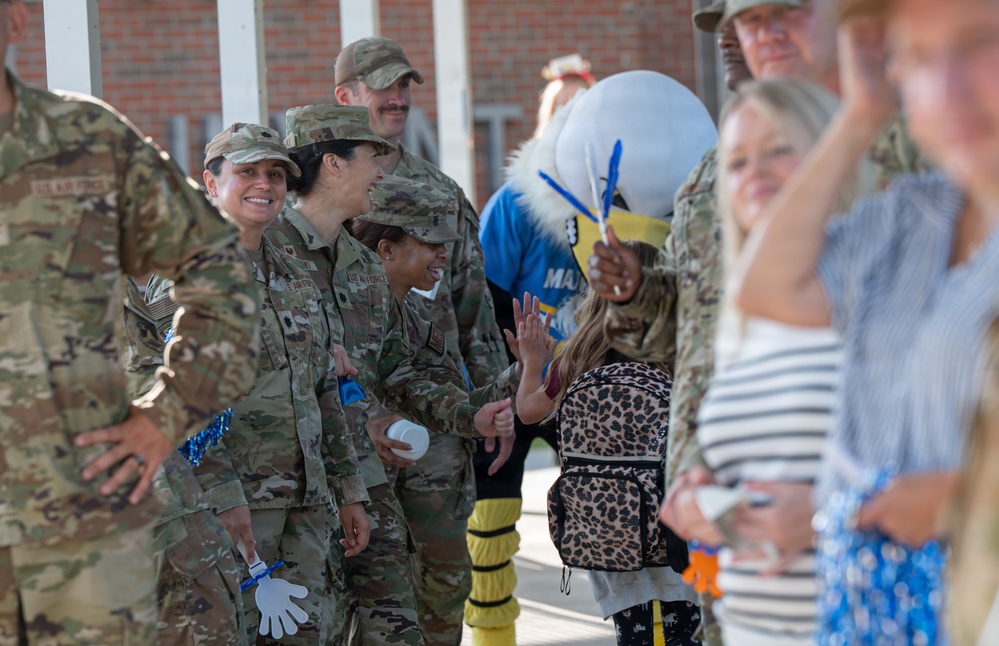 Airmen and civilians cheer students on their first day of school