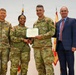 A U.S. Army certificate presentation ceremony featuring four individuals — three in Army OCP (Operational Camouflage Pattern) uniforms and one civilian in a suit. A female soldier identified by nametape as 'GORE' is receiving a Department of the Army certificate from a male soldier identified as 'CAL...' (partially visible), while 'MOORE' stands to the left. The event appears to be a formal military recognition or award ceremony.
