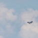 A single military jet aircraft is captured in flight against a partly cloudy sky. The aircraft appears to be a fifth-generation stealth fighter, consistent with an F-35 Lightning II, photographed at a distance. The image shows the aircraft in level flight with landing gear retracted.