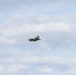 A single military jet aircraft is captured in flight against a partly cloudy sky. The aircraft appears to be a fifth-generation stealth fighter, consistent with an F-35 Lightning II design, flying at a moderate altitude. The image was taken from a ground-level perspective with the aircraft positioned near the center of the frame.