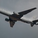 A U.S. Air Force military tanker aircraft, identified as a Boeing KC-46 Pegasus, is captured in flight against an overcast gray sky. The aircraft bears the serial number 66018 and displays 'U.S. AIR FORCE' markings along the fuselage. The aircraft appears to be climbing or in level flight with landing gear retracted.